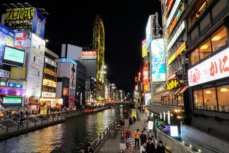 Family walking along the canal road of Dotonbori, Osaka, enjoying neon lights.