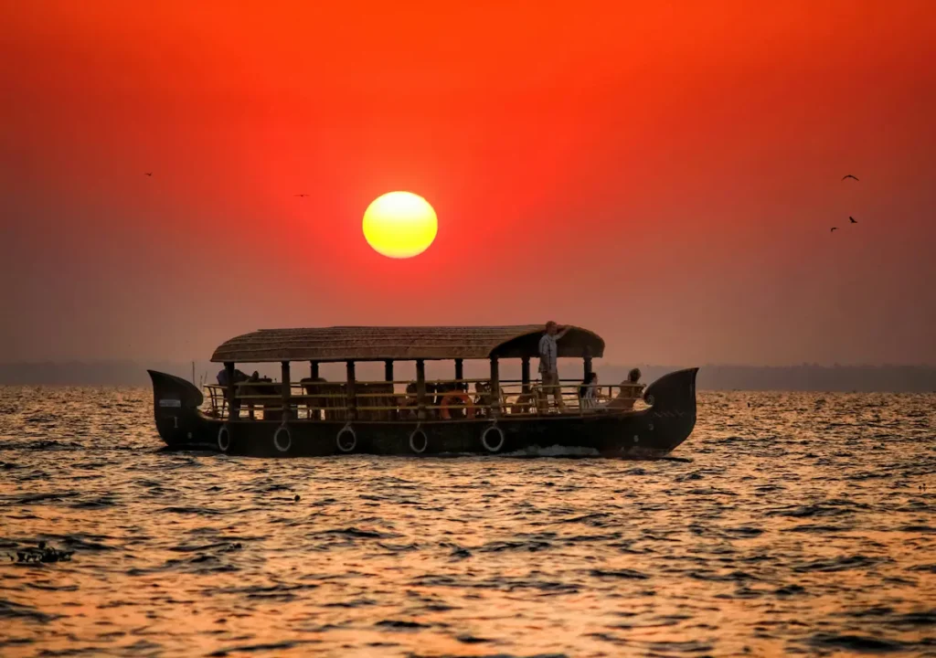 A shikara boat passing narrow waterways in Alleppey with a beautiful sunset. 