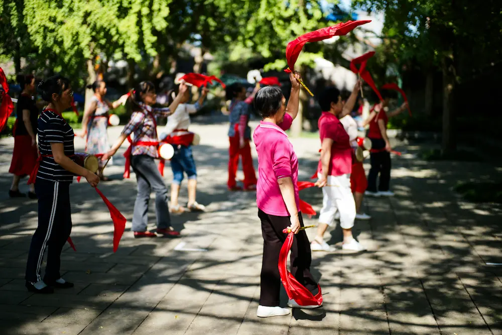 kids watching dancing grannies in a public park in China during morning activities
