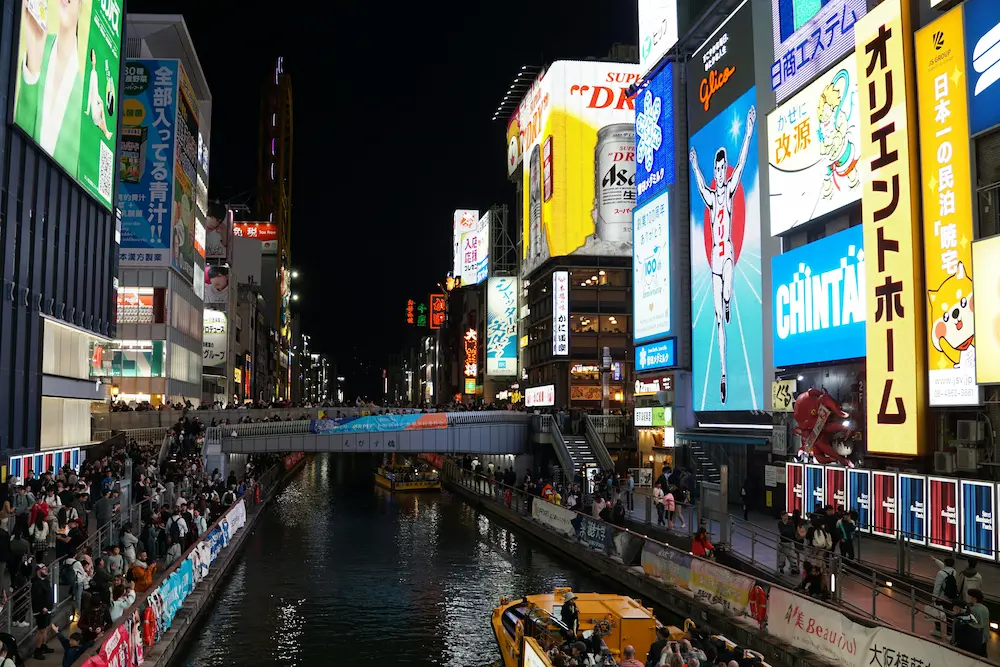Tourists standing along the Dotonbori Canal in Osaka makes it appealing but crowded.