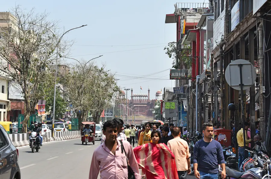 Walking through a busy market in Delhi with two young kids in front of red fort.