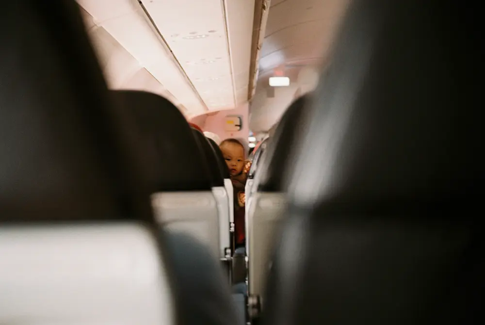 baby is looking between the seats during a long flight to Asia