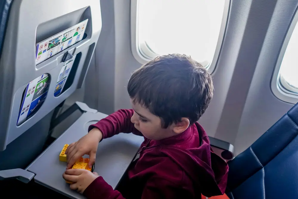 Kid is playing with Legos or small toys in airplane during a long-haul flight