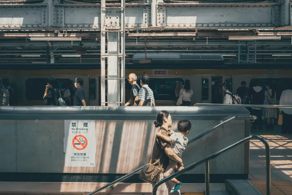 A mom carrying a kid on the staircase of Shinjuku Station, Japan.