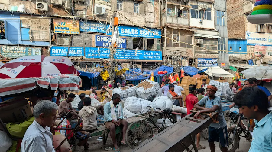 Rickshaws are waiting in a crowded old Delhi street.