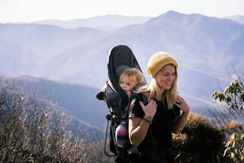 A mom carrying a toddler in a backpack child carrier used for trekking in Sapa, Vietnam