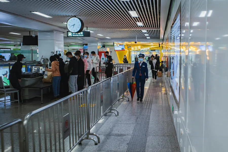 Parents lifting luggage and stroller through China train station security