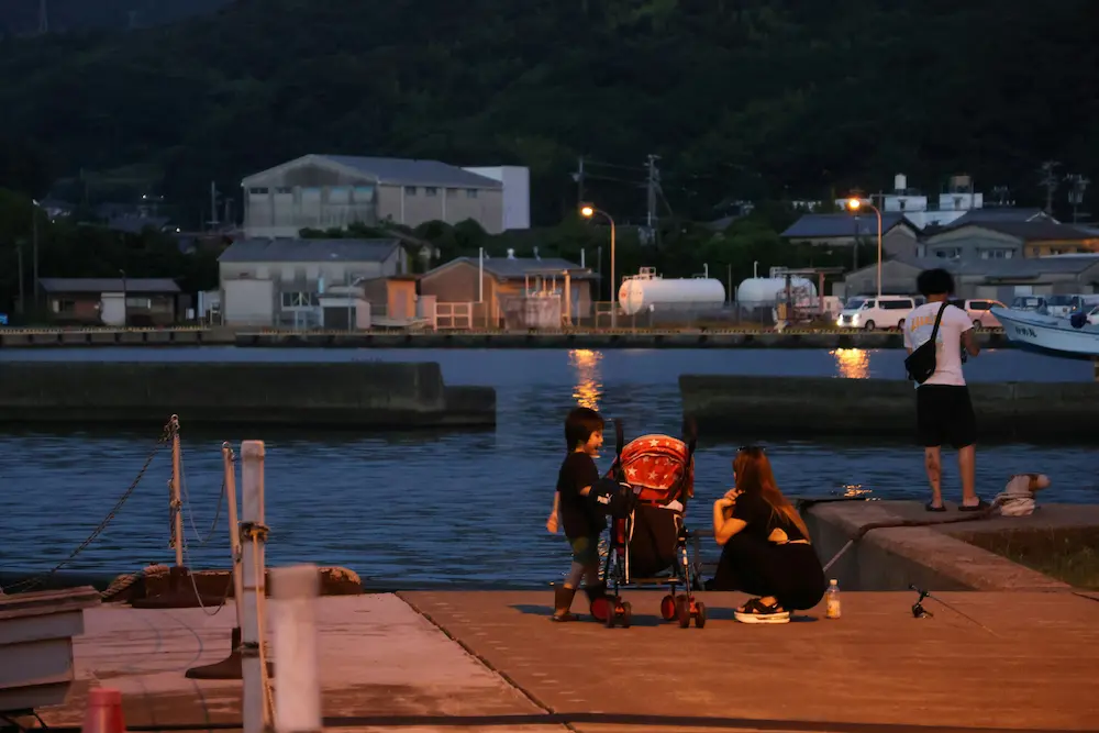 A family pushing a compact travel stroller down a wide, paved pedestrian pathway on an Osaka day trip with kids.
