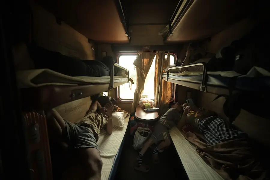 Parents and children relaxing inside a Vietnam sleeper train compartment during Vietnam train travel with kids
