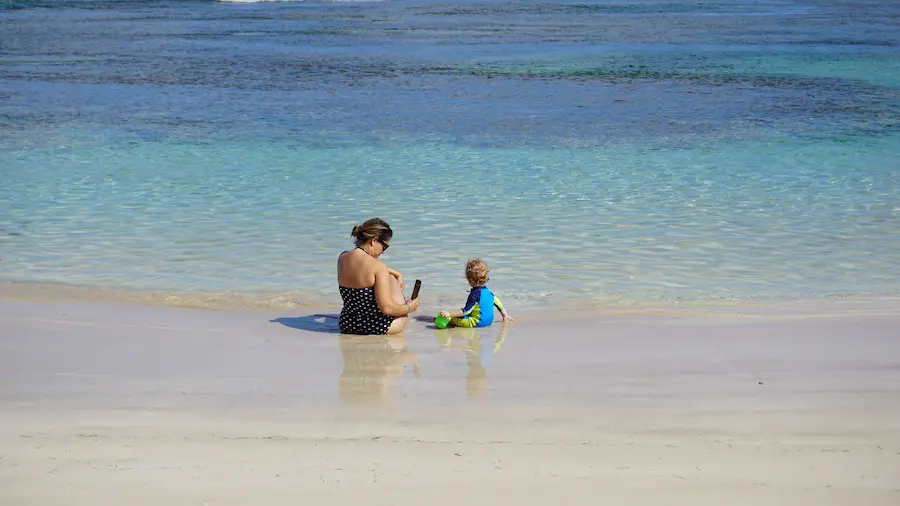 Mum sitting quietly on the beach of Semniyak, a toddler.